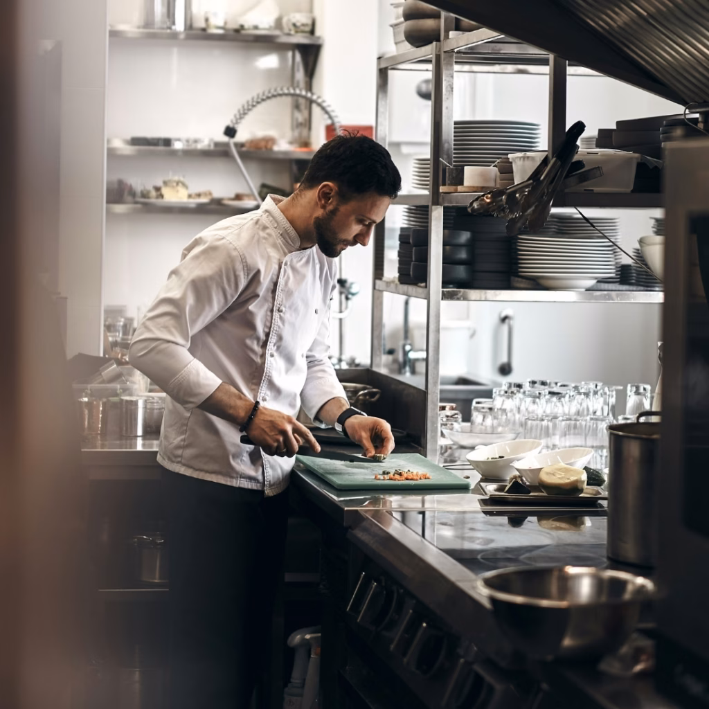 Koch in Großküche bereitet Speisen vor – energieintensive Küchenprozesse im Cateringbetrieb